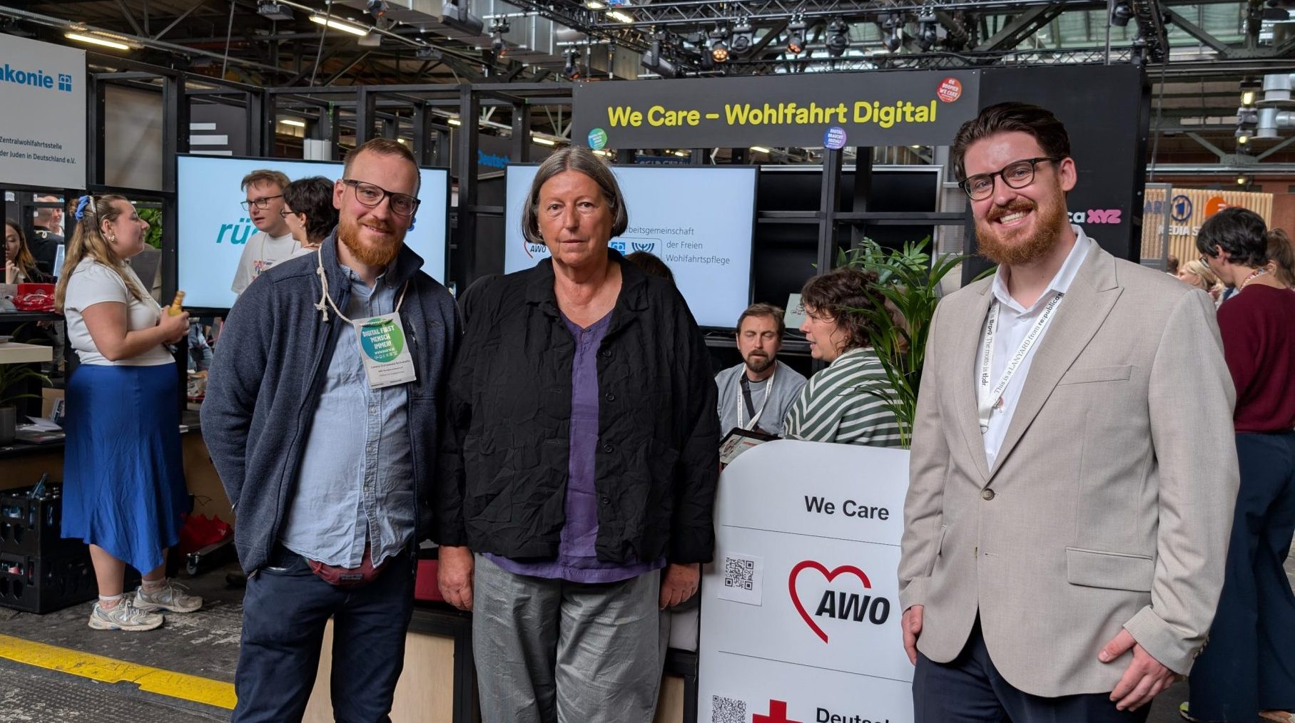 Gruppenbild von drei Personen vor einem Messestand